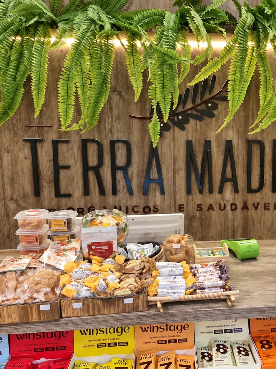 Balcão da Terra Madre com a marca em madeira e samambaias
